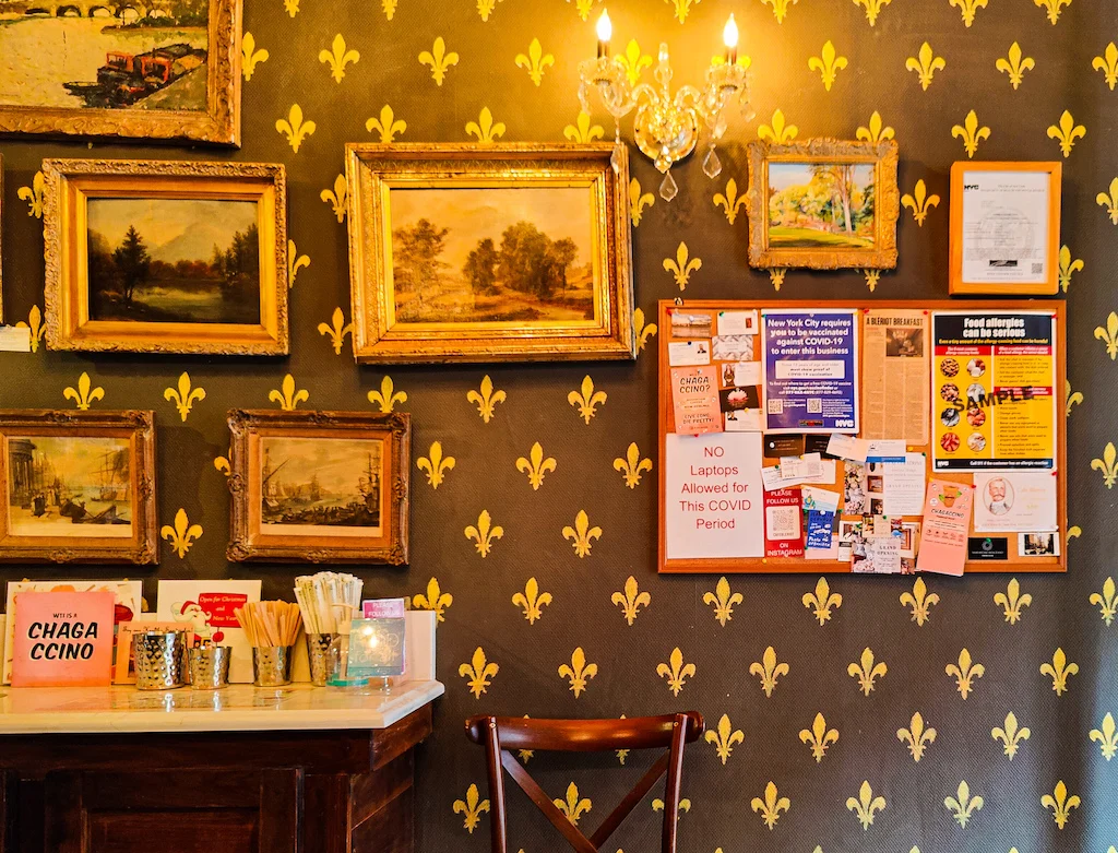 A view of the historic interior of Cafe Bierot XI. It has green wallpaper with yellow stars on it and you can see vintages lights and paintings hung on the wall. 