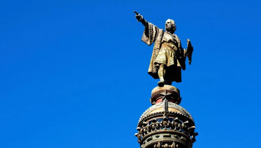 A close up view of Barcelona's Columbus Statue on a bright blue day. He has his finger pointing at America in the distance. 