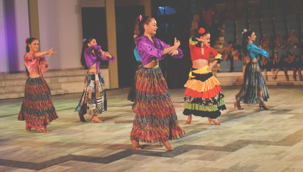 A view of five different women is vibrant shorts and skirts on-stage and dancing the flamenco in Barcelona. 