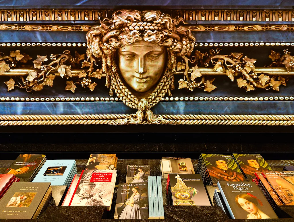 Gold and blue decor with a female head at the center of the photo stands over a selection of guide books for the museum. 