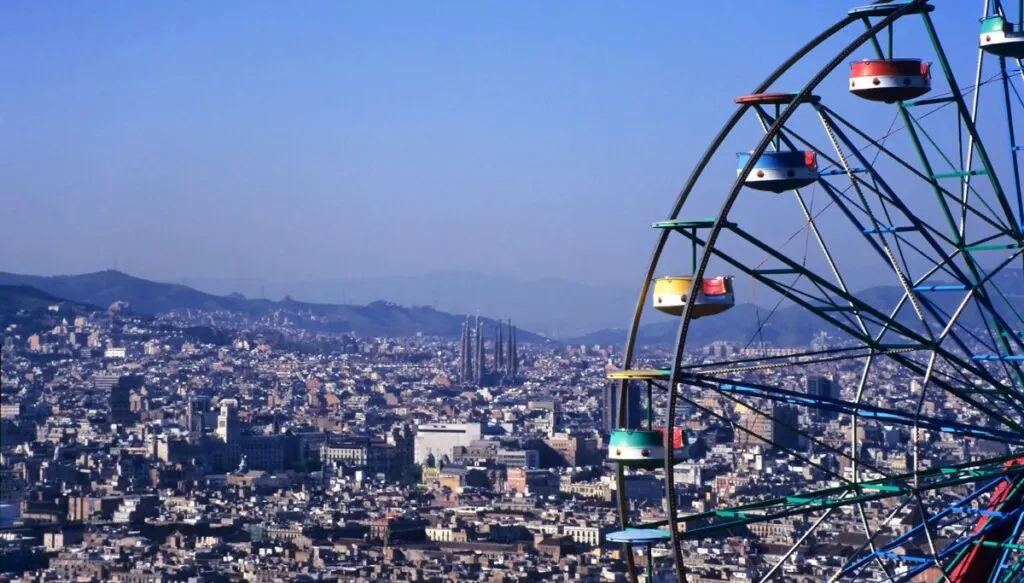 Stunning aerial view of Barcelona from the top of Tibidado. You can see part of the ferris wheel from the amusement park on the top of Tibidado in Barcelona. It's on the right and you only see part of it. 
