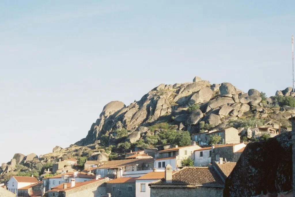 View of white homes built into the mountains with giant boulders in Monsato on a sunny day. 