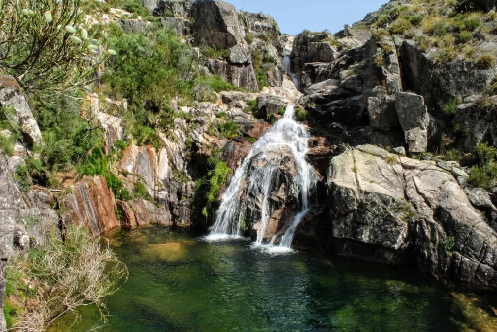 View of a waterfall cascading down a series of rock into. a blue lagoon inside Peneda-Ger&ecirc;s National Park. 