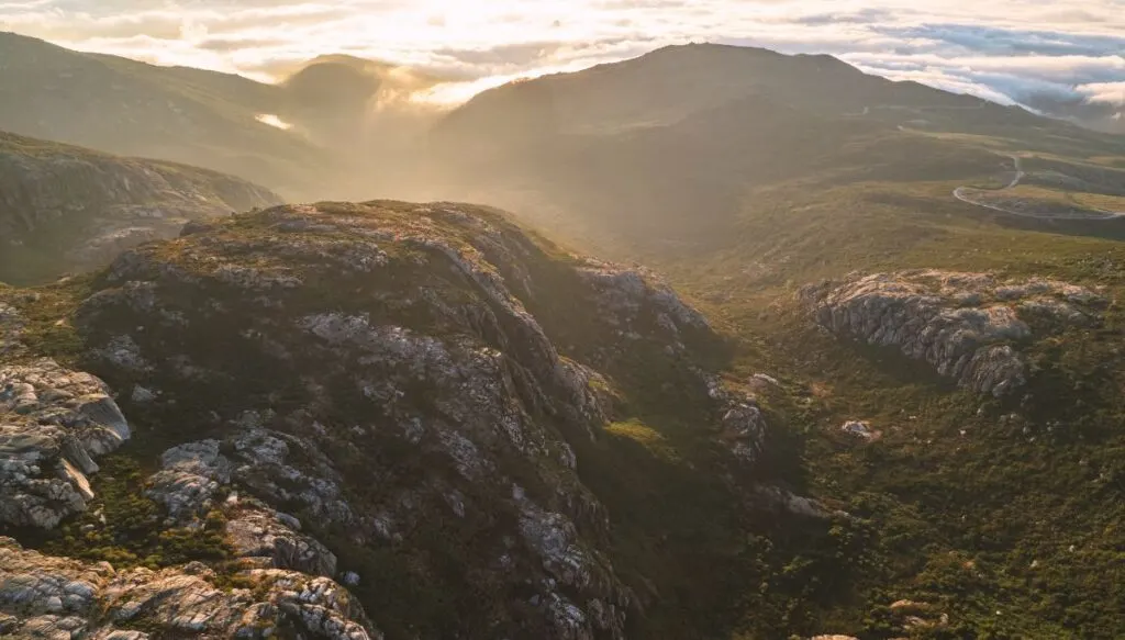 Aerial view from the top of Serra de Estrela Mountain,. You can see the clouds in the distance and the sea as well as rocks and grass on a sunny day. 