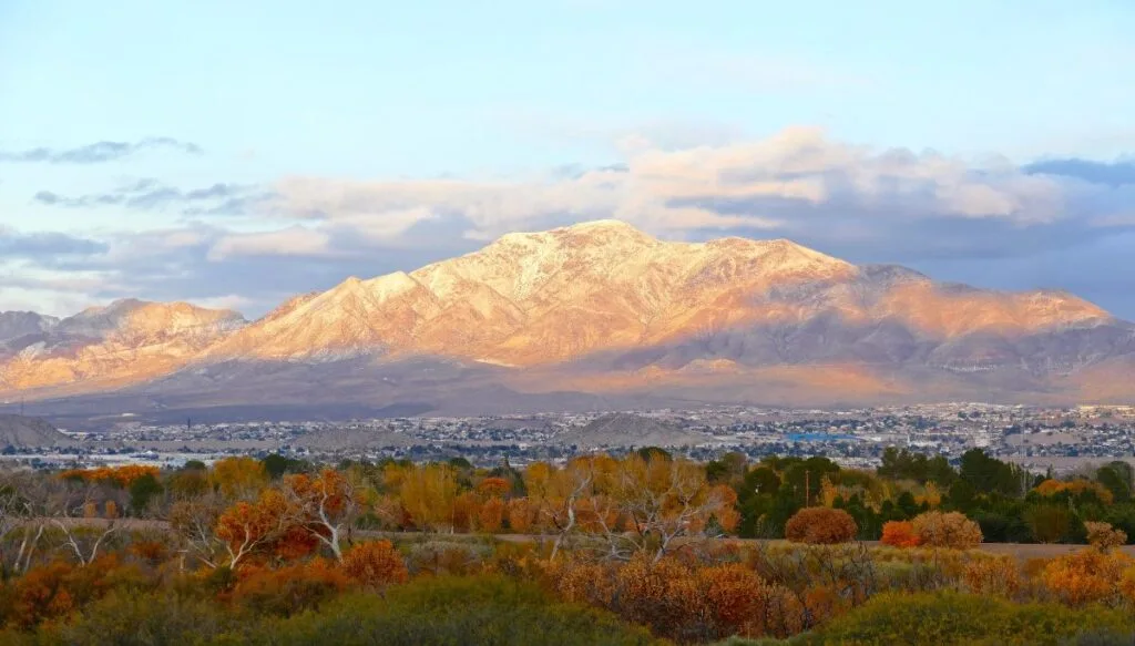 View of the franklin Mountains covered in snow with fall foliage in front and El Paso at the base of the mountains. 