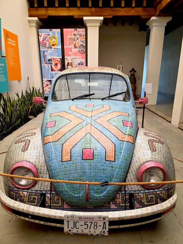 View of a small VW bug with geometric colors and patterns on it inside of MUFI. 