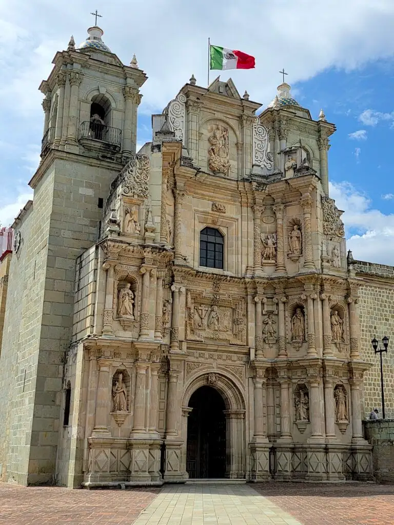View of the exterior of Le Soledad Church with a Mexican flag hanging from the top. 
