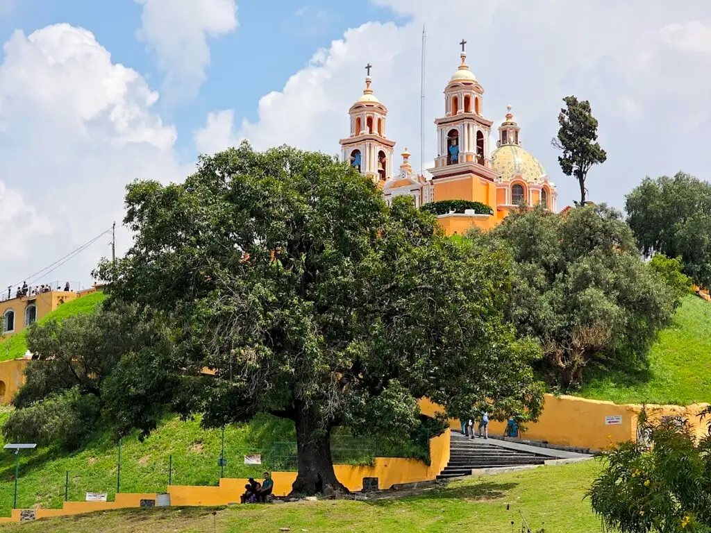View of the great pyramid with a yellow and white church sitting on top on a sunny day. 