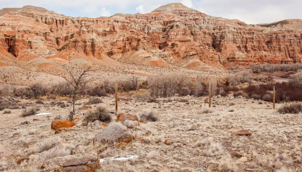 View of the red rock mountains of Dubois and a barren landscape at the base of the mountains. 