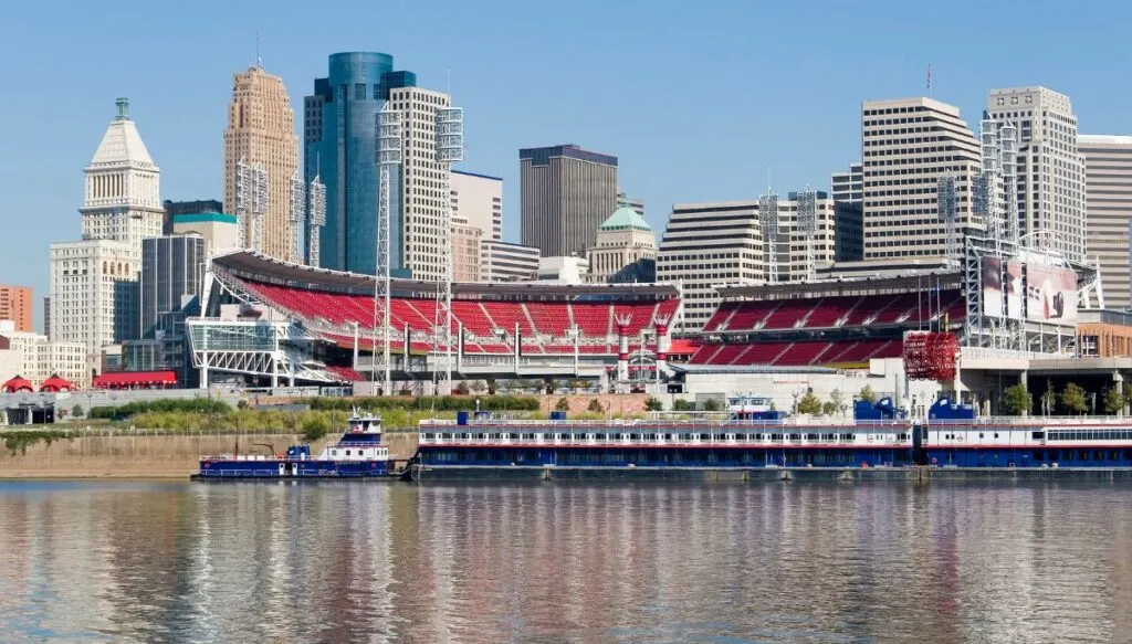 View of a large outdoor stadium sitting along the edge of the river with the Cincinnati skyline in the background. 