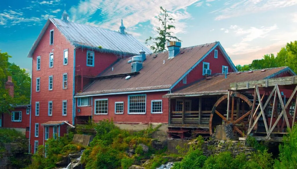 View of an old red building with a wooden mill that sits along the edge of a forested cliff in Ohio. 