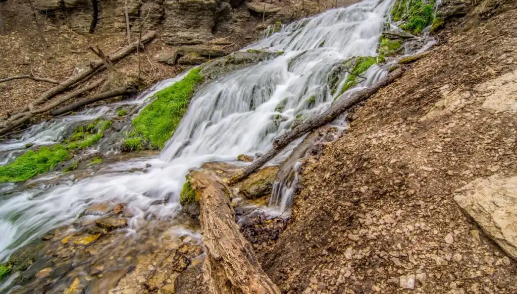 View of a small waterfall with dirt and moss around it in Decorah, Iowa. 
