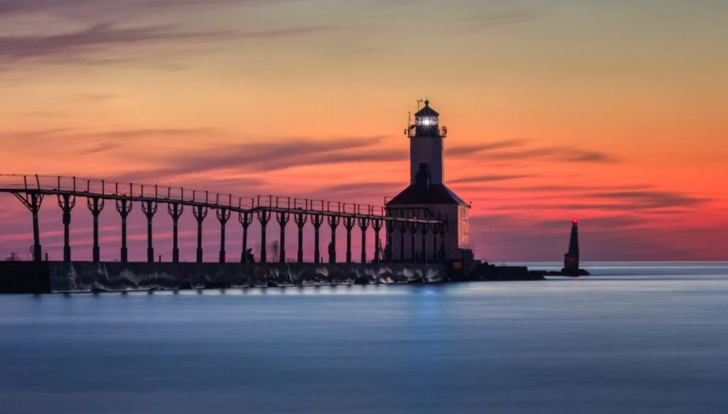 View of a walkway leading out to the East Pierhead Lighthouse with the sun setting in the background. This is one of the most beautiful places in Indiana. 