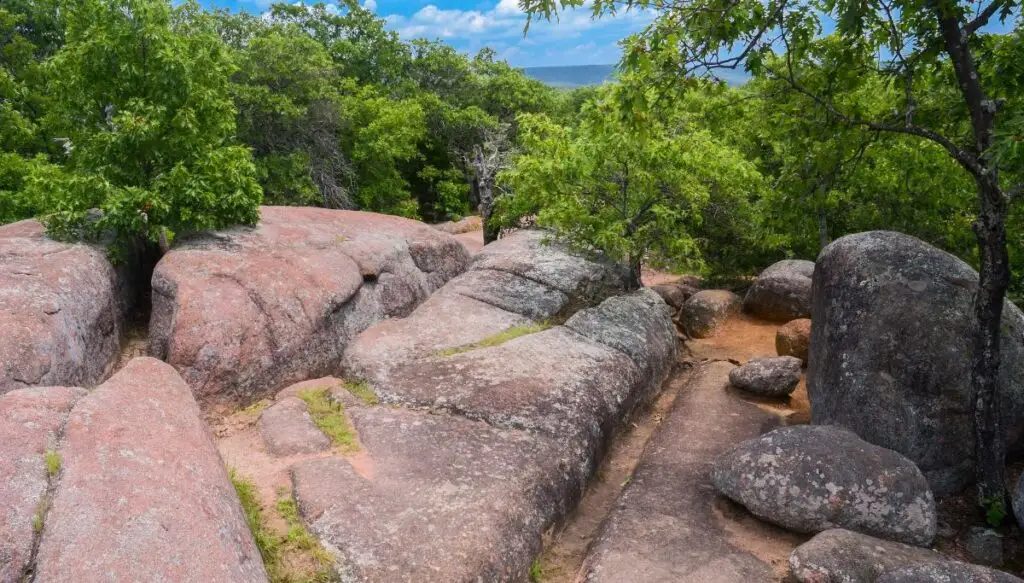 View of unique rocks formations surrounded by trees on top of a hill in Elephant Rocks State Park. 