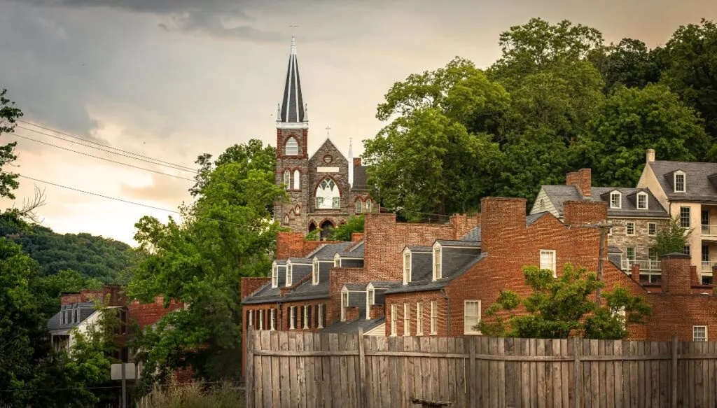 View of charming brick buildings and a brick church in the background on a cloudy day in Harpers Ferry. 
