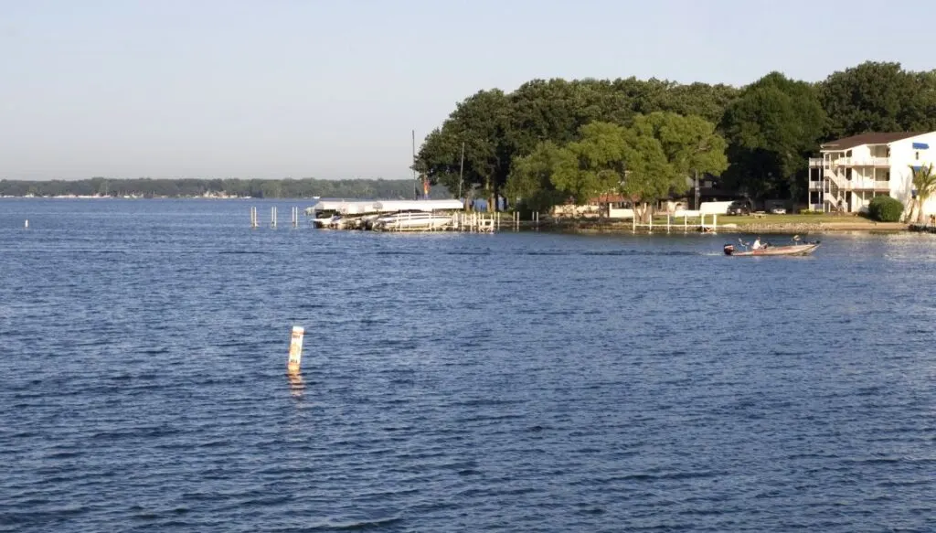 View of a piece of land jutting out into Okoboji Lake. You can see white buildings and piers on the lande. 