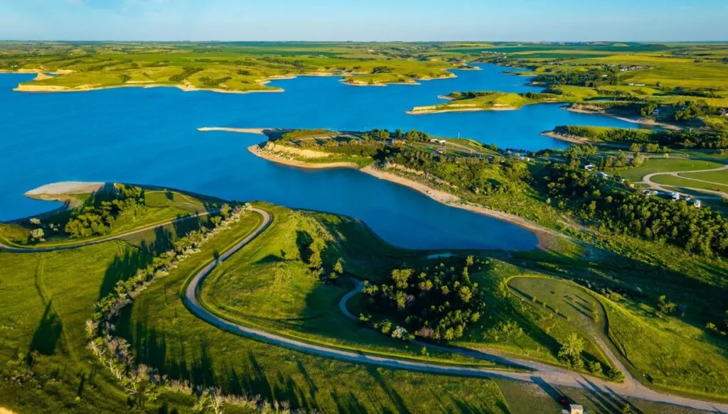 Aerial view of the green shores of Lake Sakakawea. You can see grassy areas along the shore as well as roads.