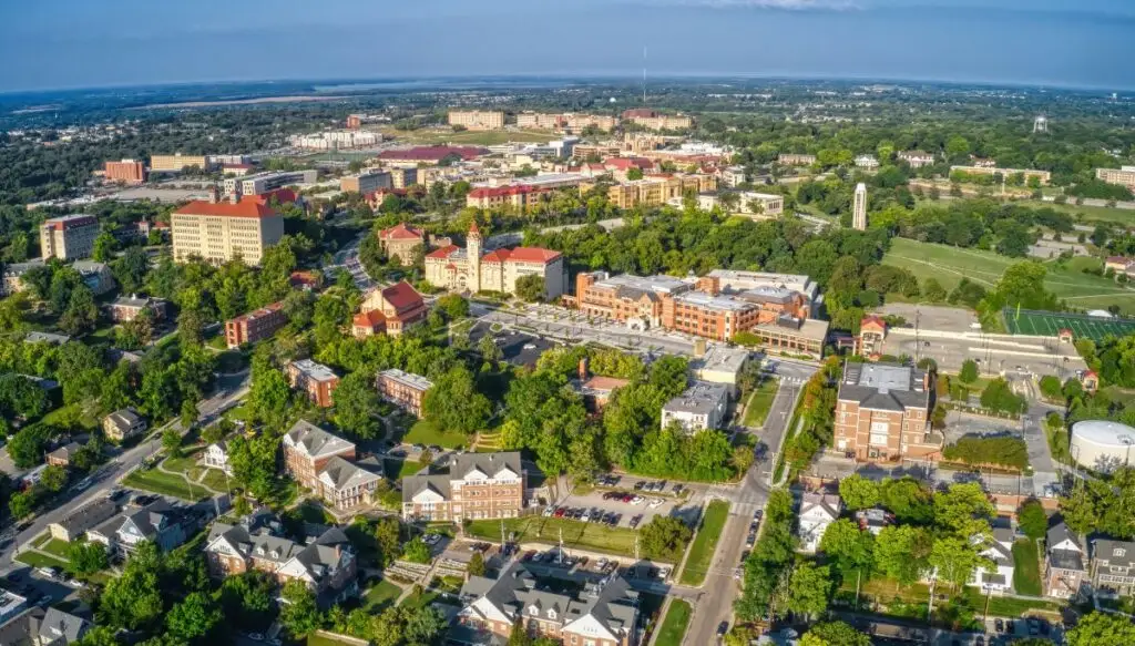 Aerial view of the roads and buildings in Lawrence, Kansas that are surrounded by green trees. 