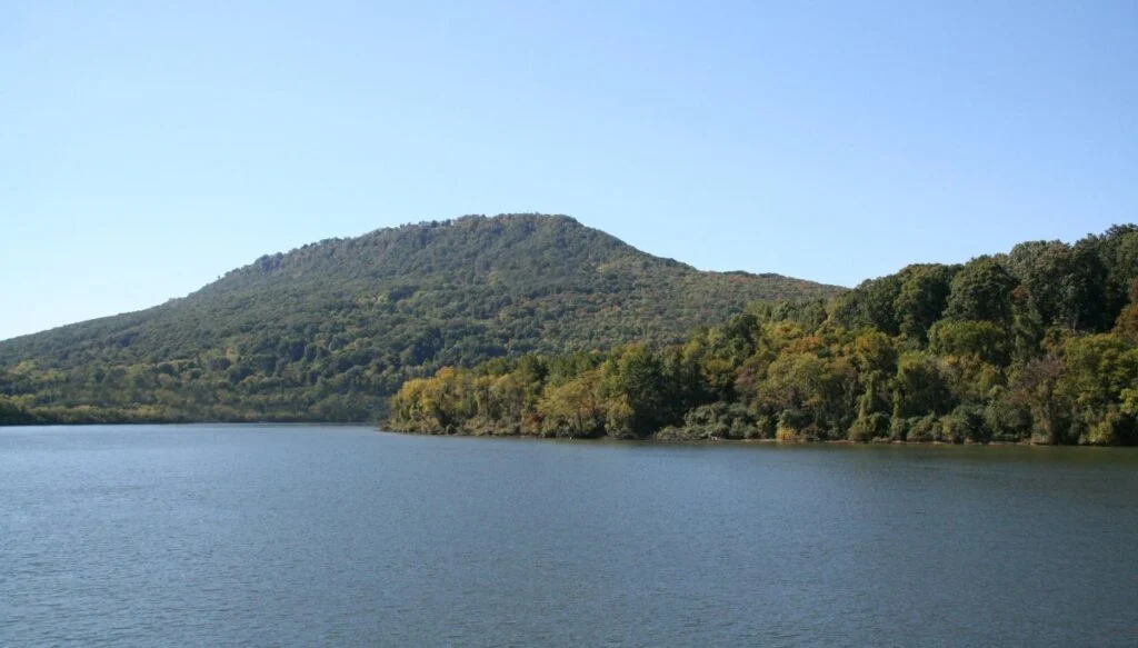 View of Lookout Mountain with tons of green trees sitting along the edge of a blue river. 