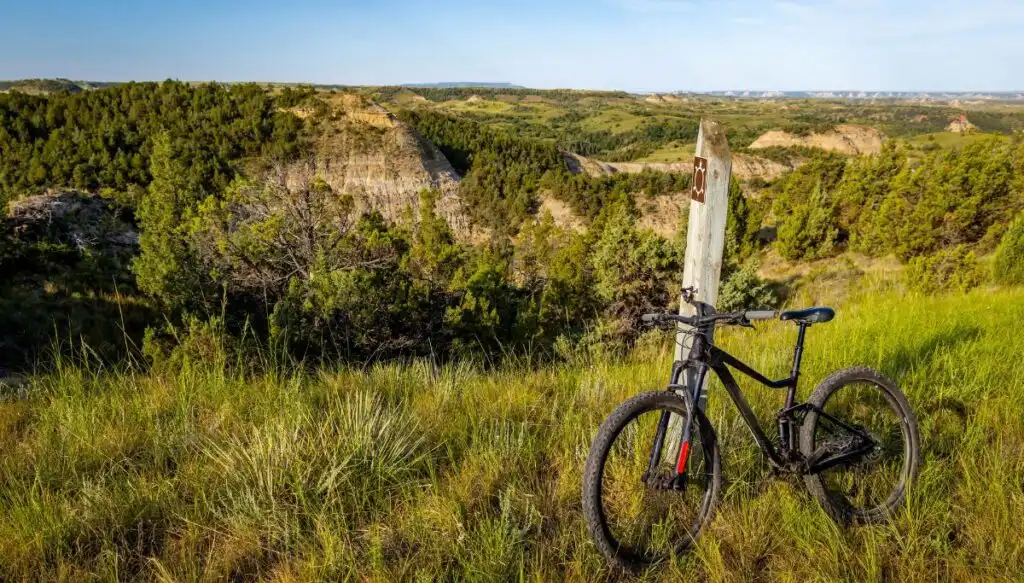 View of a black bike sitting along a wooden post with sweeping views of North Dakota along the Maah Daah Hey Trail.