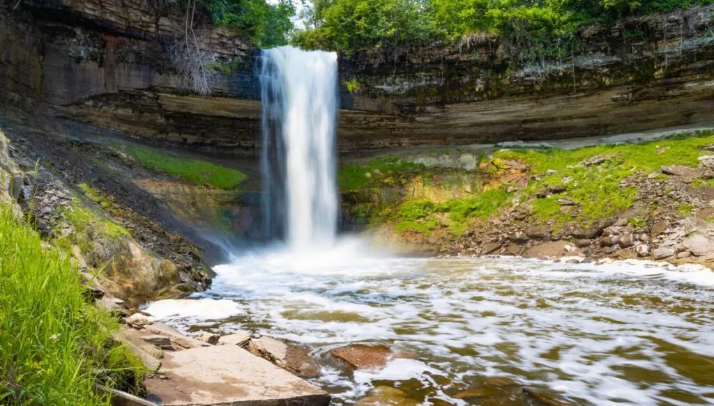 View of Minnehaha Falls plunging down over the edge of a rock into a river below just outside of Minneapolis. 