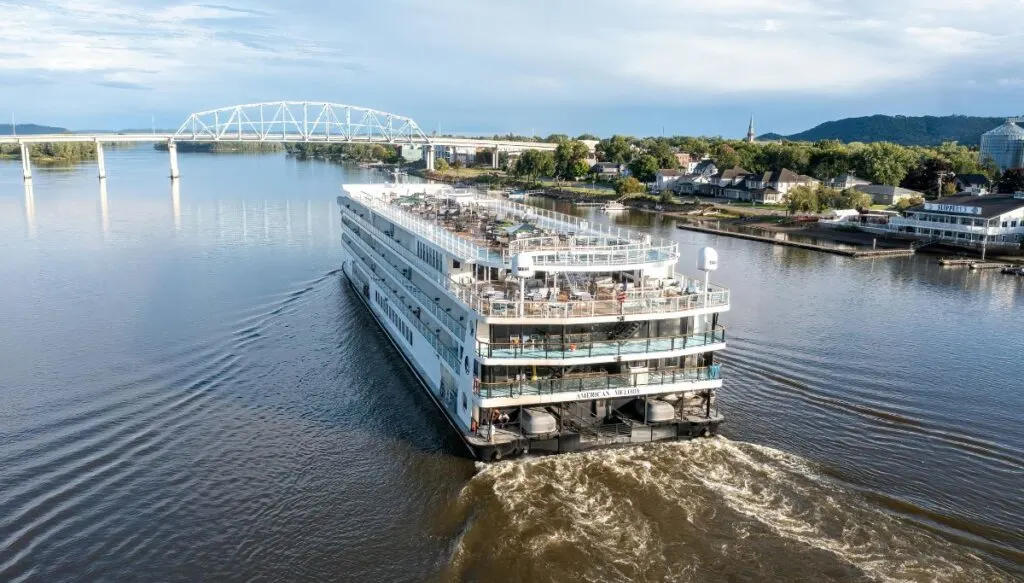 View of the back of a white river cruise boat sailing down the Mississippi River. 
