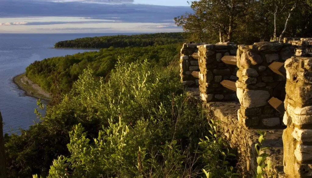View of the water and trees along the coast from an overlook with a stone fence at Peninsula State Park. 