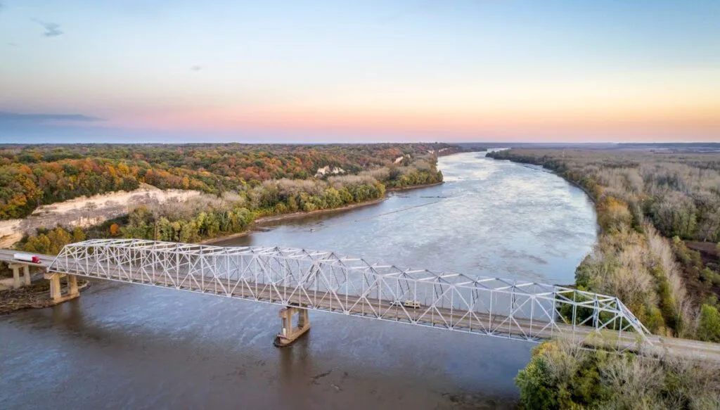 Aerial view of a metal bridge over a river near Rocheport. You can see the sun setting in the background. 