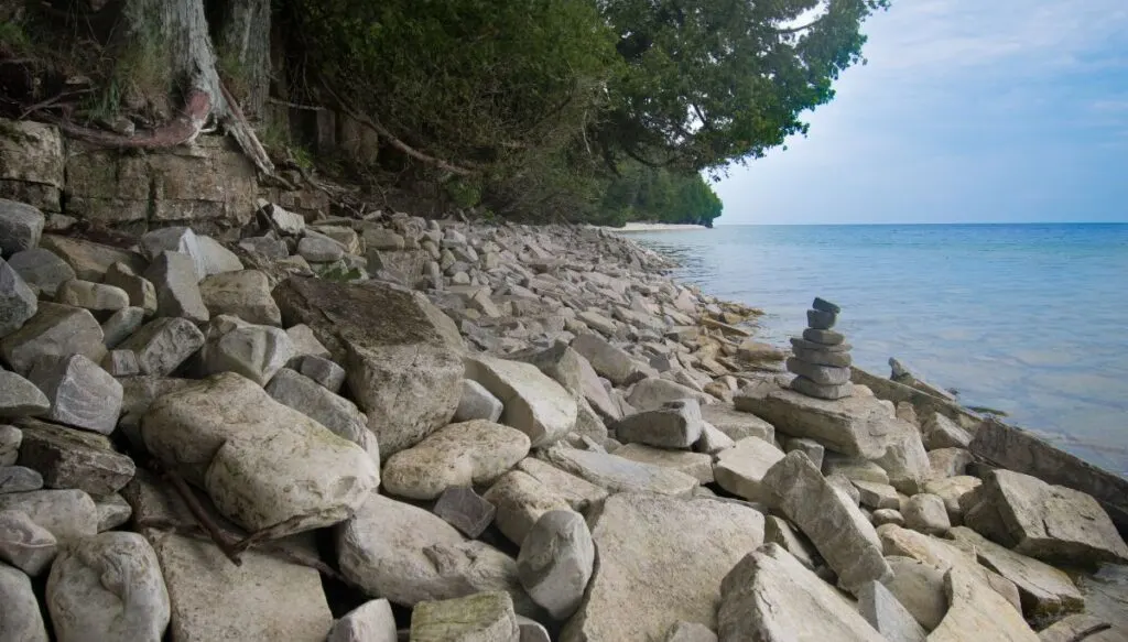 View of rocks and cute little rock formations along the shore of Rock Island with evergreen trees in the background. 