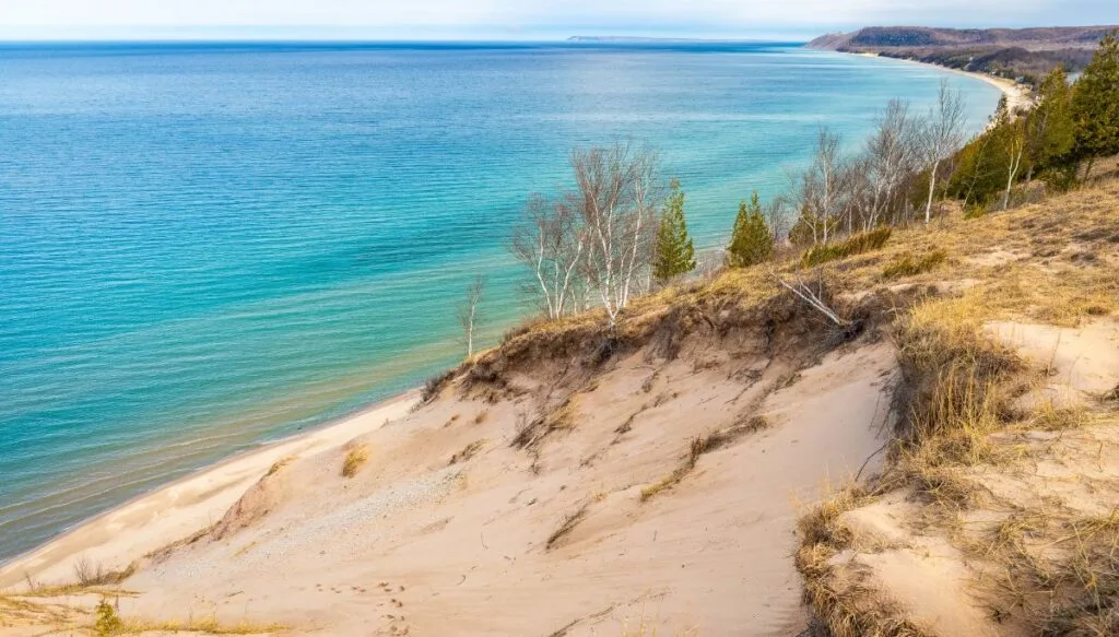 View of bright blue water and the sand dunes that makes up the Sleeping Bear Dunes National Lakeshore. 