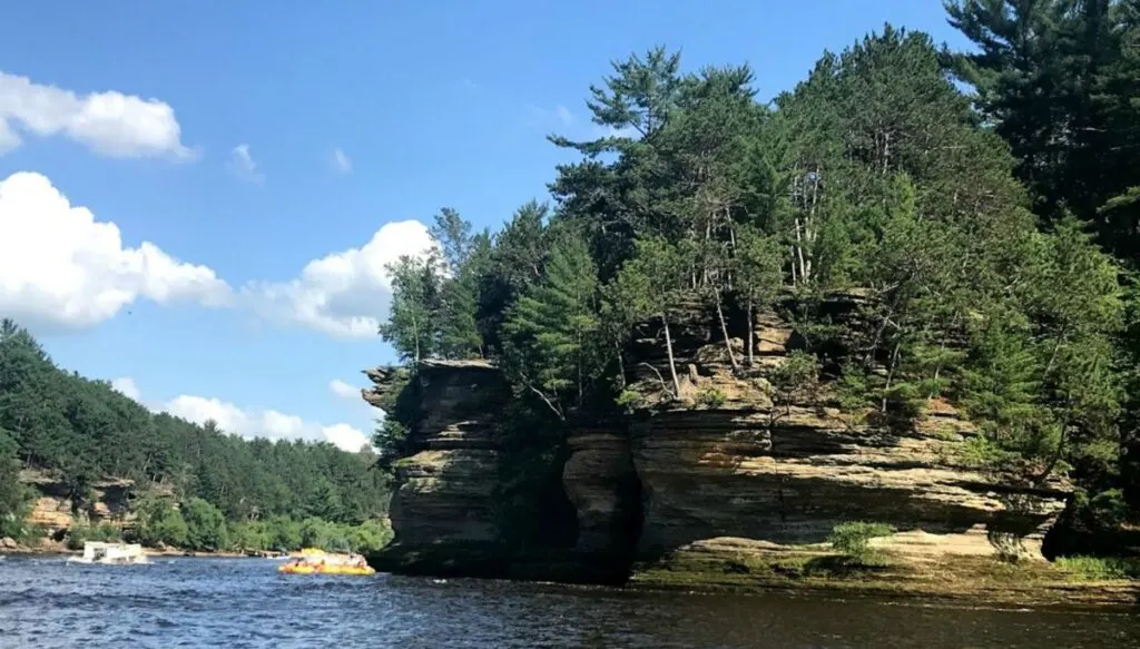 View of pine trees growing atop of the sheer cliffs of an island in the middle of a kaje in the Wisconsin Dells. 