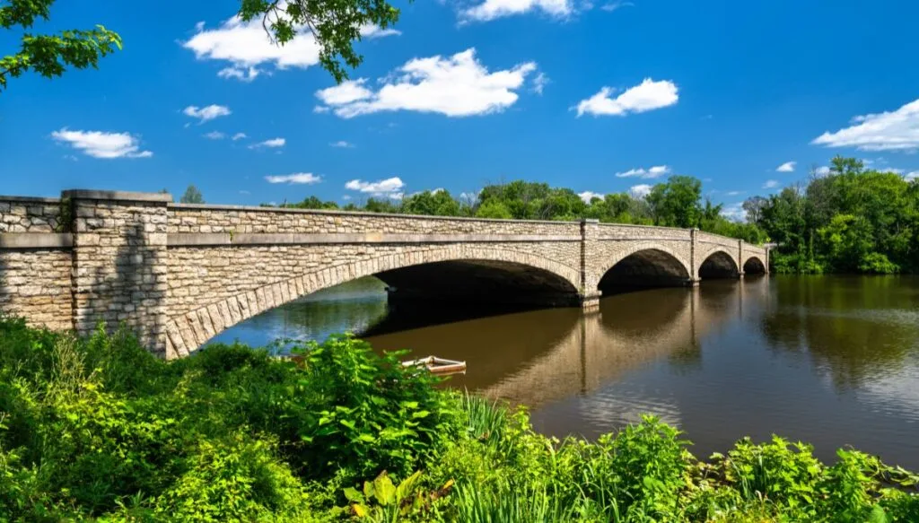 View of a stone bridge surrounded by greenery going over Carnegie Lake near Prinseton, New Jersey. 