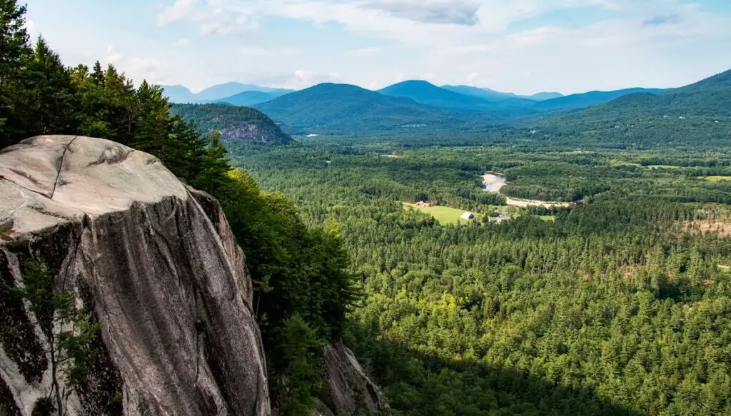 View of the vast pine forests and mountains in the background at Cathedral Ledge. You can also see a rock formation to the left. 