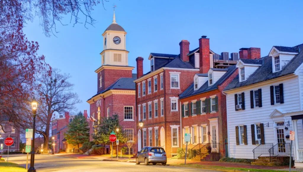 View of the Colonial-style buildings in downtown Dover with one gray car on the street as the sky goes dark. 