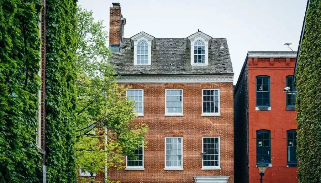 View of the historic brick homes of Fell's Point. The houses are Colonial-style and are surrounded by green trimmed hedges.