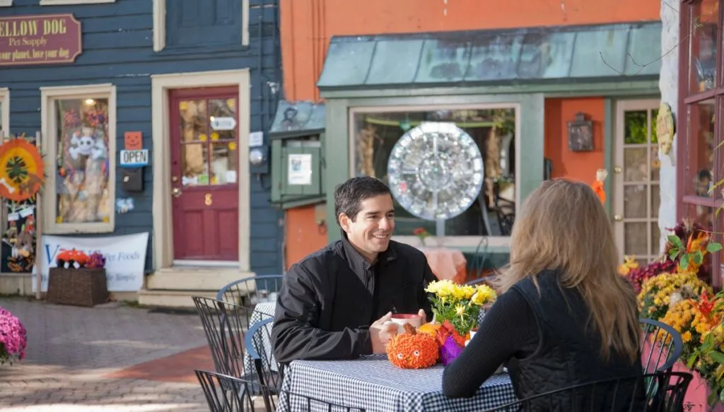 View of quirky shops with fall decor in Frenchtown. You can see a couple sitting at a table in the foreground. 
