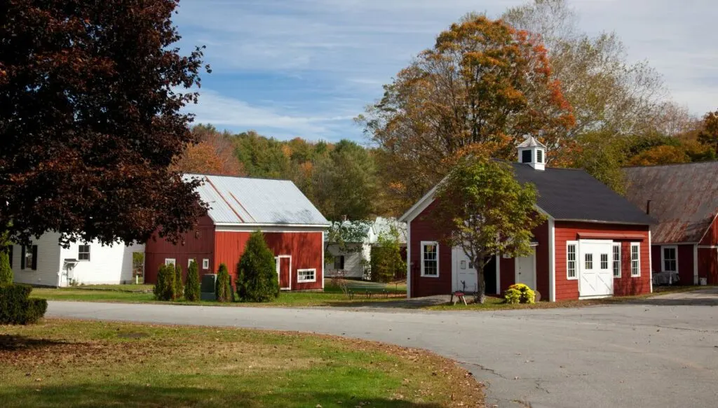 View of small, red, barn-like buildings surrounded by fall foliage in Grafton. This is one of the most beautiful places in Vermont. 