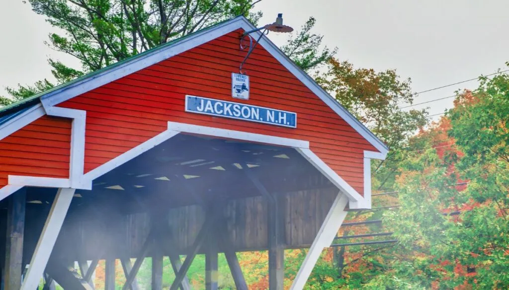 View of the red covered bridge in Jackson with trees around it changing colors because it's fall. 