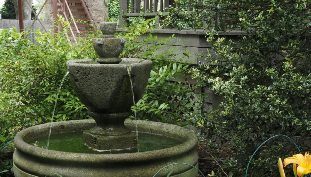 View of a little three tier stone fountain surrounded by greenery in Lambertville.