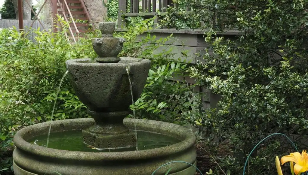 View of a little three tier stone fountain surrounded by greenery in Lambertville. 