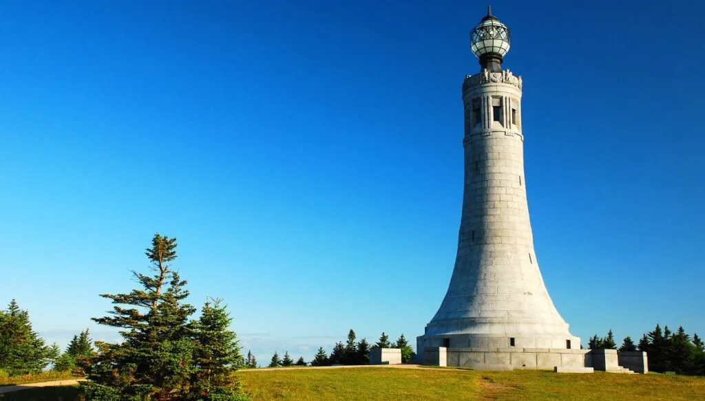View of the war memorial tower on the summit of Mount Greylock on a sunny day. You can see trees in the background too. 