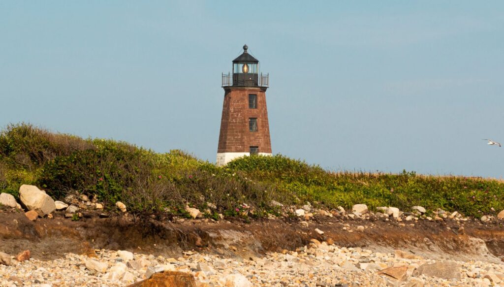 View of a small brick lighthouse poking up through green grass in Narragansett.