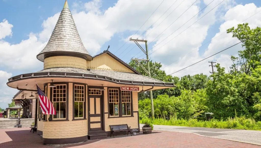 View of an old railway station with Victorian-style architecture in New Hope with an American flag out front. 