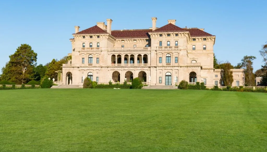 View of a large mansion in Newport that is the Breakers with a sprawling green lawn in front of the mansion. 