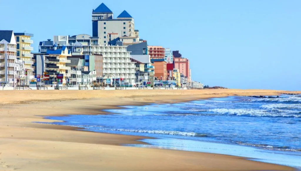 View of the beach at Ocean City on a sunny day with tall buildings in the back along the edge of the sand. 