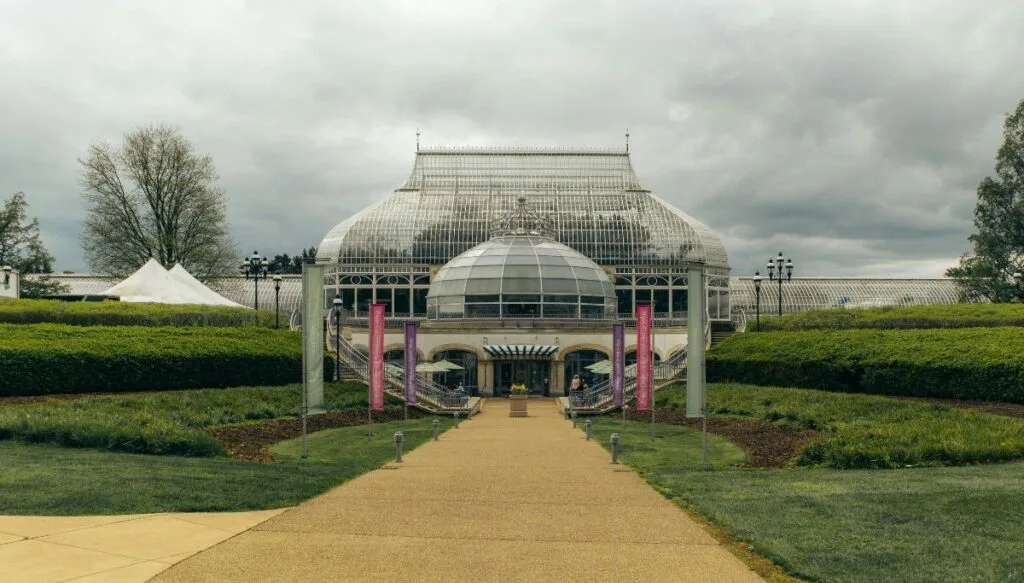 View of a central pathway leading to a greenhouse on a cloudy day 