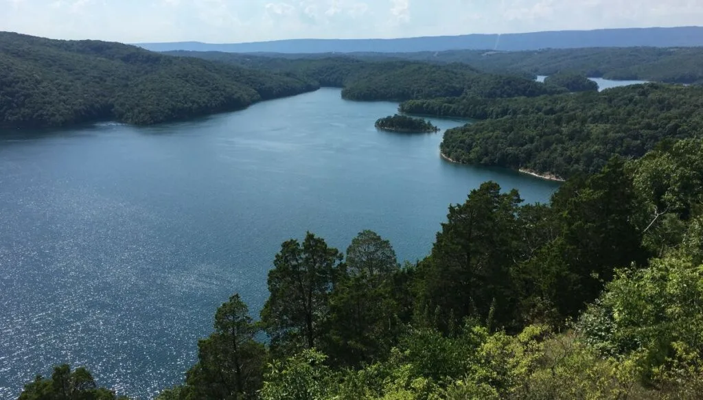Aerial view of Raystown Lake in Pennsylvania. You can see the blue lake on the left surrounded by tall green trees with trees in the distance. 