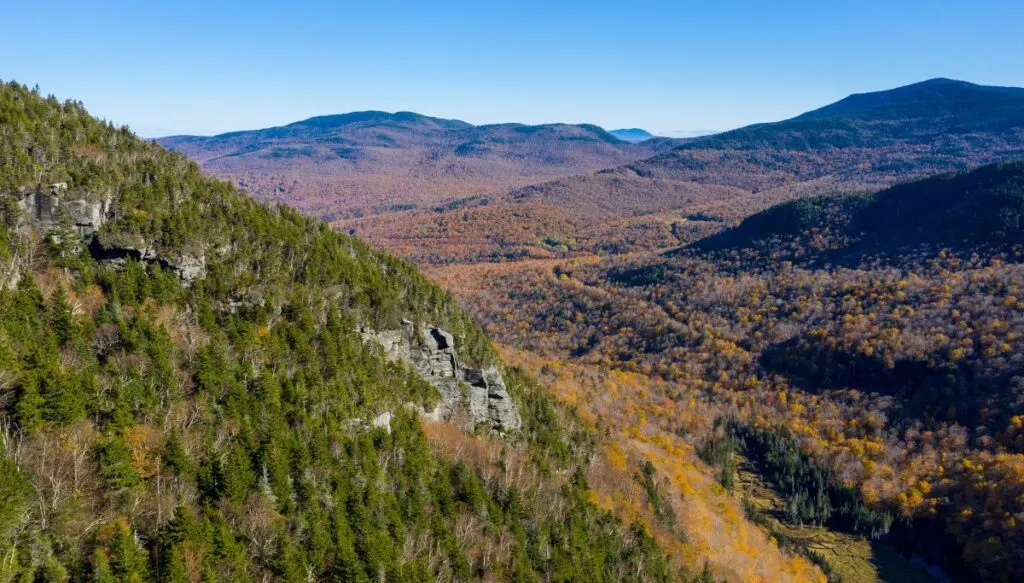Aerial view of the green pine trees and trees turning yellow around Smuggler's Notch in Vermont. 