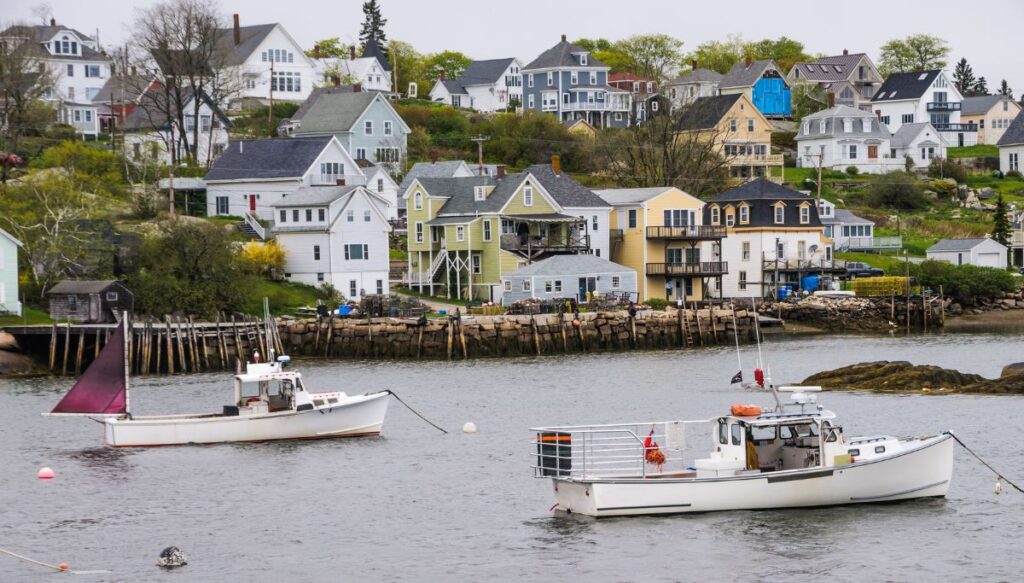 View of homes sitting along the water and white lobster boats sitting in the harbor in Stonington.