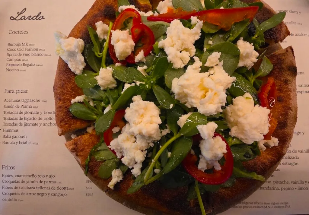 Aerial view of a pizza from Lardo with greens and red peppers and white cheese. 